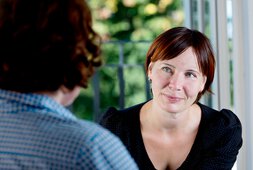 Eine Frau ist in einem Gespräch mit einer anderen Person verwickelt | © clarkandcompany - istock